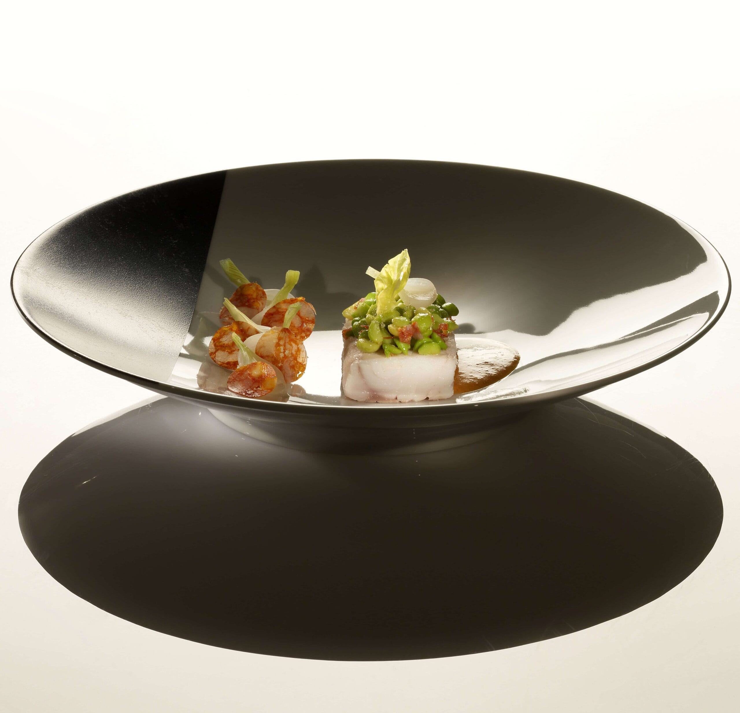 Filetto di spigola, piselli con cipollotti, panna e striscioline di chorizo dolce